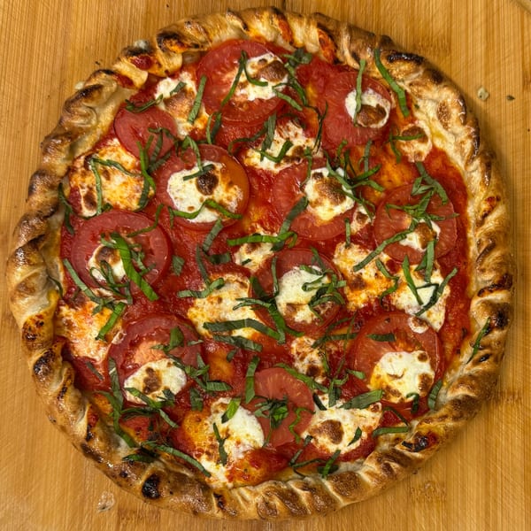 Heavy Metal Pizza's Margherita pizza, topped with fresh tomatoes, mozzarella, and basil, on a wooden board.