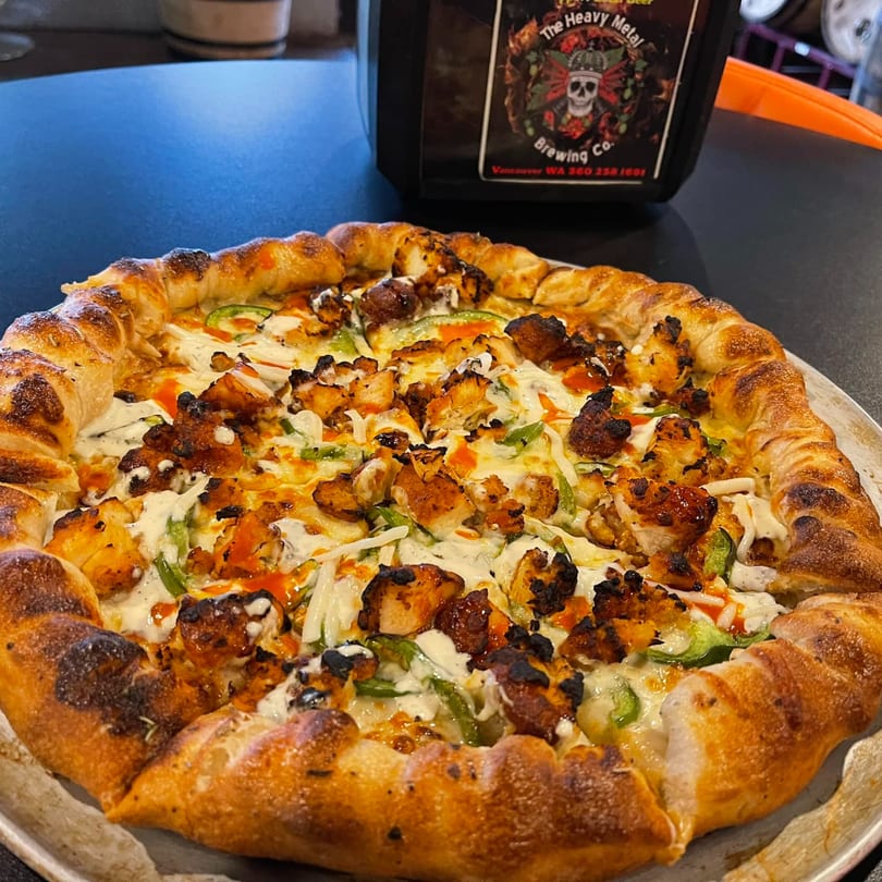 Heavy Metal Pizza's chicken pizza with green peppers, white sauce, and hot sauce drizzle.